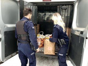 policjant, policjantka przy tyle radiowozu gdzie są torby i paczki dla dzieci