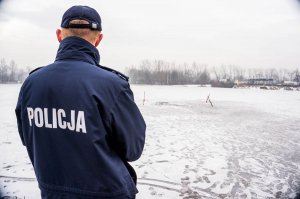 policjant stojący przy zamarzniętym stawie