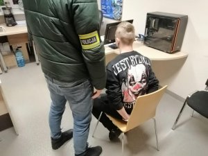 Policjant kryminalny z zatrzymanym w pomieszczeniu biurowym