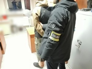Policjant kryminalny z zatrzymanym w pomieszczeniu biurowym