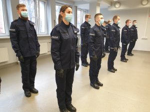 Zdjęcie kolorowe - sala odpraw, policjanci stoją w postawie zasadniczej przed śubowaniem