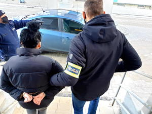 zdjęcie kolorowe - policjant prowadzi zatrzymaną 17-latkę do samochodu