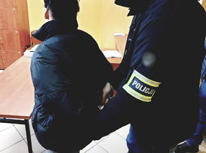 zdjęcie kolorowe - policjant zapina kajdanki na ręce 17-latki