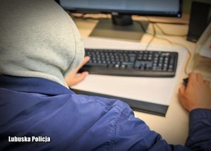 mężczyzna w kapturze przy komputerze - zdjęcie poglądowe