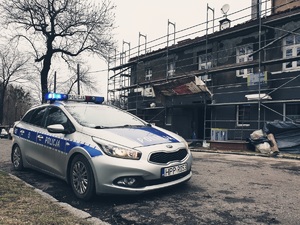 kamienica, przed nią stojący radiowóz policji