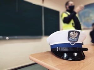 zdjęcie z wizyty policjantów w szkole - czapka policjanta z drogówki leży na stoliku, on w tle