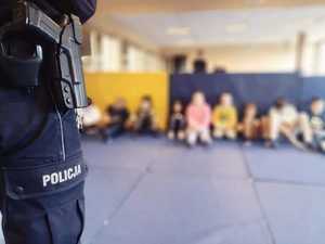 sala sportowa, siedzące dzieci, na pierwszym planie noga policjanta z napisem policja