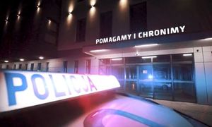 napis policja na radiowozie, w tle budynek z napisem pomagamy i chronimy - zdjęcie poglądowe