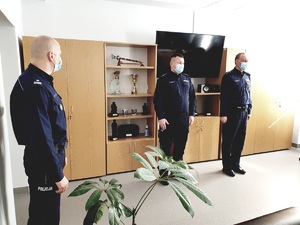 gabinet komendanta po lewej stoi zastępca komendanta miejskiego, na środku dwóch awansowanych policjantów, za nimi meble biurowe