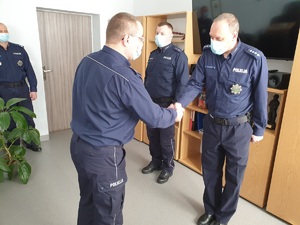 gabinet komendanta po lewej stoi zastępca komendanta miejskiego, na środku dwóch awansowanych policjantów, komendant składa gratulacje