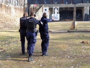strzelnica zewnętrzna - dwóch policjantów strzela w ruchu, za nimi idzie instruktor