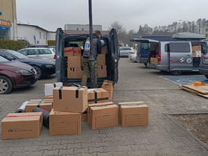 parking, samochody przed pudełka kartonowe, mężczyzna pakuje pudła z darami do samochodu, zdjęcie FB 13orzesze