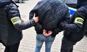zdjęcie poglądowe - dwóch policjantów po cywilu prowadzi zatrzymanego z kajdankami na rękach