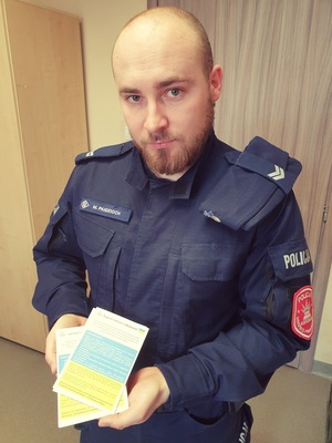 policjant trzyma w rękach ulotki dla uchodźców z Ukrainy