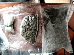 na biurku worki foliowe po lewej mały z białym proszkiem, w środku większy z suszem roślinnym i po prawej duży z szuszem