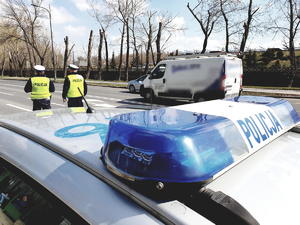 policjanci z drogówki na ulicy, radiowóz na pierwszym planie