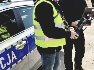 dwóch operatorów drona przy radiowozie