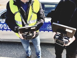 dwóch operatorów drona przy radiowozie