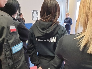 uczeń i dwie uczennice tyłem pomiędzy nimi w tle widać stojącą policjantkę