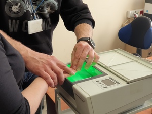 policyjny technik skanuje odciski palców jednej z uczennic