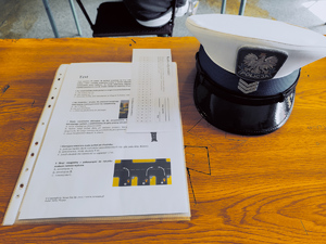 biurko na którym leży karta konkursowa i obok czapka policjanta z drogówki