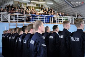 Hala gimnastyczna, stojący nowo przyjęci policjanci, w tle publiczność