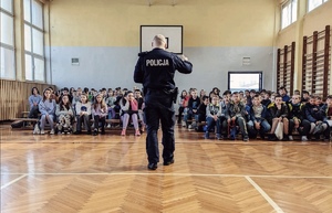 Policjant prowadzący prelekcje dla uczniów w auli Szkoły
