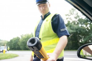 policjant trzymający w ręku alkotest wyciągnięty w kierunku kierowcy - zdjęcie poglądowe z archiwum