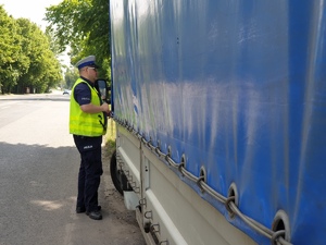 policjant przy samochodzie ciężarowym rozmawiający z kierowcą, który popełnił wykroczenie