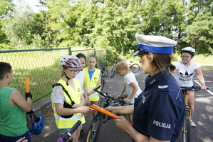 policjantka rozdaje dzieciom odblaskowe opaski
