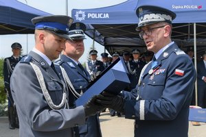 Trzej policjanci, nagrodzony dzielnicowy przyjmuje statuetkę od komendanta wojewódzkiego, w tle jako trzeci komendant miejski policji w rudzie śląskiej
