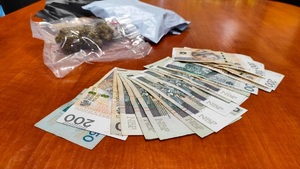 woreczki z narkotykami i banknoty 50, 100 i 200 złotych leżące na blacie biurka