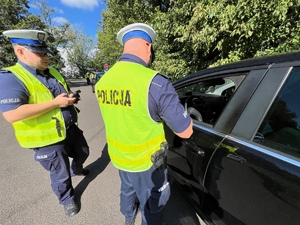 policjanci w trakcie kontroli kierowcy czarnego samochodu osobowego