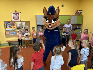 sala przedszkolna, dzieci stoją i witają się z wiewiórką maskotką rudzkiej policji, która jest w niebieskim munurze