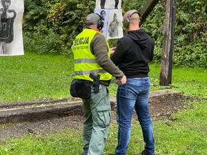 zajęcia strzeleckie na strzelnicy otwartej, instruktor strzelecki z policjantem w cywilu przy tarczach