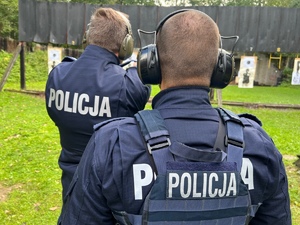 zajęcia strzeleckie na strzelnicy otwartej, policjanci w mundurach, jeden instruktor stoi za strzelającym kontrolując jego ćwiczenie