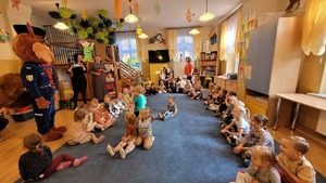 sala przedszkolna, dzieci siedzą i patrzą na maskotę Sierżant Rudą