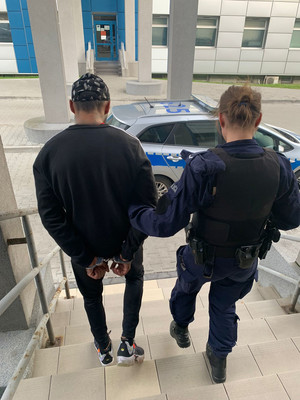 policjantka z zatrzymanym schodzi po schodach do radiowozu