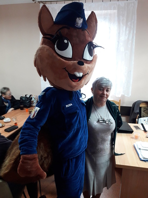 maskotka policji - ruda wiewiórka z seniorką pozującą do zdjęcia w sali stowarzyszenia