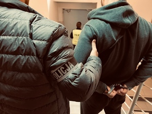policjant z zatrzymanym schodzą po schodach wewnątrz komendy