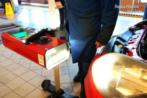 diagnosta sprawdza ustawienie świateł w czerwonym samochodzie