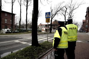 policjanci z drogówki stojący przy drodze i przejściu dla pieszych, budynki, drzewa, jesienna aura - zdjęcie poglądowe