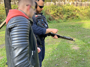 strzelnica otwarta - instruktor strzelectwa pokazuje policjantowi pionu kryminalnego strzelbę gładkolufową