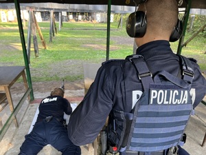 strzelnica otwarta - policjant prewencji leży strzelając z karabinu, za nim stoi instruktor