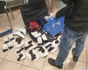 na podłodze leżą rozłożone ochraniacze do sportów walk wschodnich, przed stojący mężczyzna widoczny do połowy
