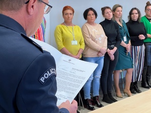 sala narad w której zgromadzili się pracownicy cywilni sala narad w której zgromadzili się pracownicy cywilni, na pierwszym planie rudzki Komendant odczytujący list Komendanta Głównego Policji, w tle stojące panie