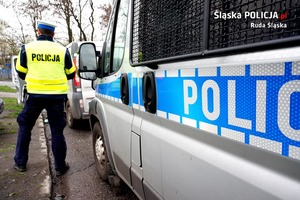 zdjęcie, policjant stojący przed policyjnym radiowozem