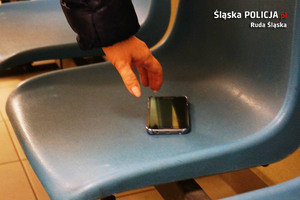 zdjęcie poglądowe przedstawia krzesło, leżący telefon i ręka sięgająca po niego