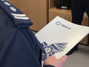 zdjęcie przedstawiające komendanta z teczką okolicznościową policji