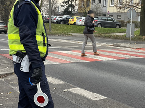 zdjęcie przedstawia policjanta drogówki przy przejściu dla pieszych po którym idzie kobieta